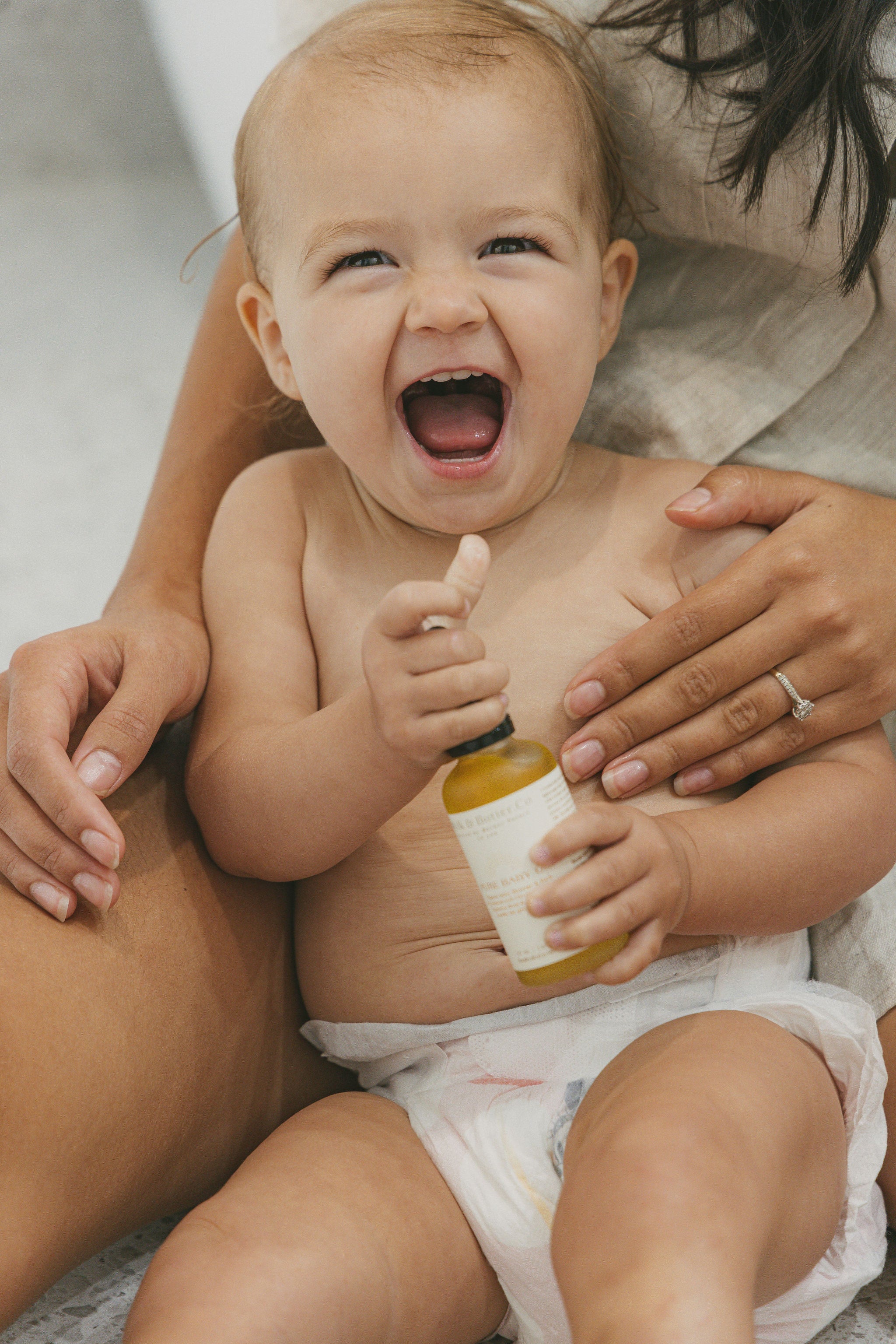 Lifestyle shot of baby holding pure baby oil